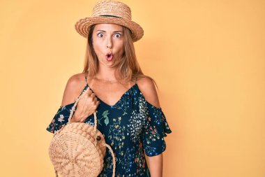 Orta yaşlı İspanyol kadın elinde hasır çanta tutan şapkalı korkmuş ve ağzı açık bir şekilde şaşırmış, inançsız bir yüz. 