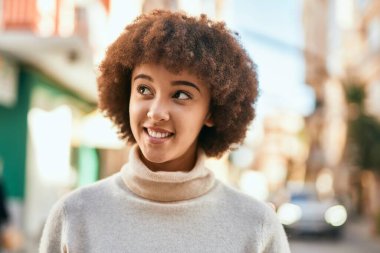 Genç İspanyol kız gülümseyerek şehirde mutlu mesut dikiliyor..