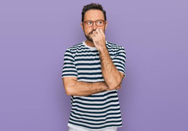 Sıradan kıyafetler ve gözlük takan orta yaşlı bir adam gergin görünüyor ve elleri ağızdan tırnak yiyor. anksiyete. 