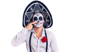 Arka planda ölü kostümü giymiş bir adam parmak parmağa ve buruna, neşeli bir şekilde gülümsüyor. güzellik konsepti 