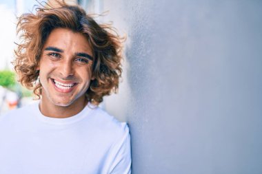 Genç yakışıklı İspanyol gülümseyen mutlu bir adam şehrin duvarına yaslanıyor.