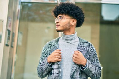 Genç Afro-Amerikan iş adamı ciddi bir ifadeyle şehirde duruyor..
