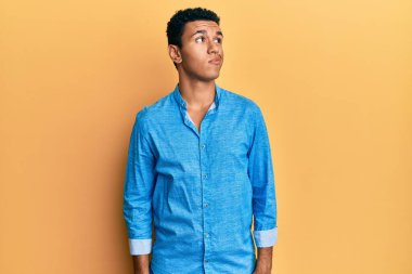 Gündelik kıyafetler giyen genç Arap adam gülümsüyor, yan tarafa bakıyor ve düşünüyor.. 