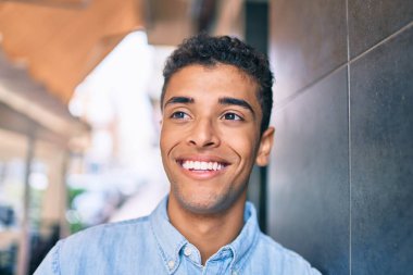 Genç Latin adam gülümseyerek şehirde mutlu mesut yürüyor..