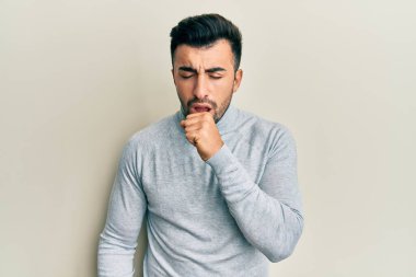 Günlük kıyafetler giyen genç İspanyol adam kendini iyi hissetmiyor ve soğuk algınlığı veya bronşitin belirtisi olarak öksürüyor. sağlık hizmeti kavramı. 