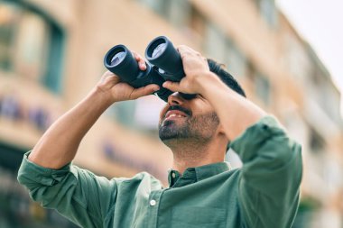 Genç İspanyol gülümseyen adam şehirde dürbünle yeni bir fırsat arıyor..