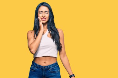 Güzel İspanyol kadın günlük kıyafetler giyip diş ağrısı ya da diş hastalığından dolayı ağızlarına acı dolu bir ifadeyle dokunuyor. dişçi 