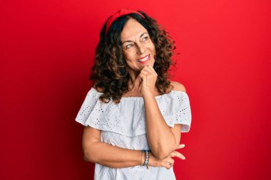 Orta yaşlı İspanyol kadın gündelik kıyafetler giyip kameraya bakıyor kollarını kavuşturup gülümseyerek ve çenesini kaldırarak. Olumlu düşünmek. 