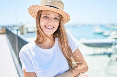 Genç sarışın kadın tatilde mutlu bir şekilde gülümsüyor. Kentin caddesinde korkuluklara yaslanıyor.