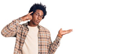 Afro saçlı, sıradan giyinmiş, gözlüklü, kafası karışmış ve avuç içi açık, fotokopi alanı gösteren ve alnını işaret eden yakışıklı Afro Amerikalı bir adam. Bunu bir düşün.. 