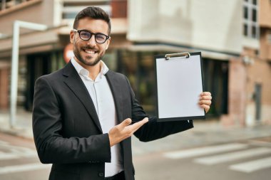 Genç İspanyol işadamı gülümsüyor. Şehirde elinde bir pano var..