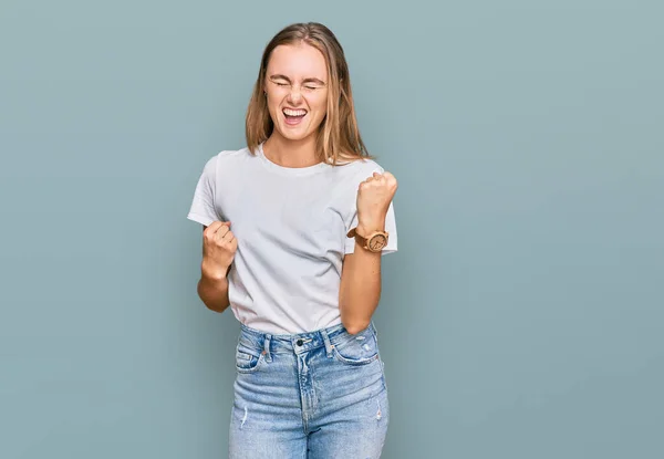 Hermosa Mujer Rubia Joven Con Camiseta Blanca Casual Celebrando Sorprendida — Foto de Stock