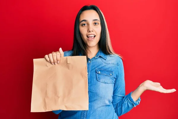 Jovem Hispânica Segurando Levar Saco Papel Celebrando Realização Com Sorriso — Fotografia de Stock