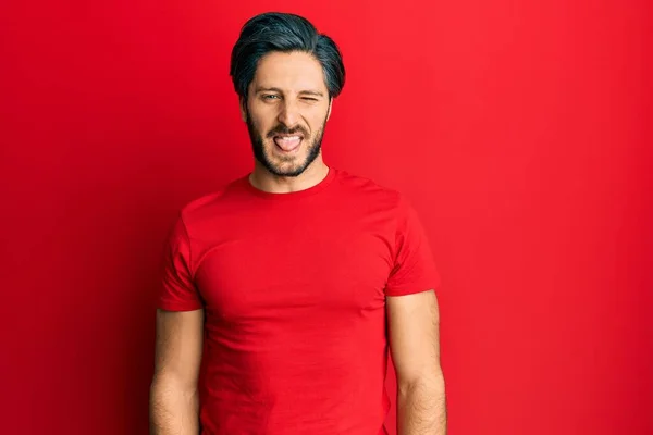 面白い表情で楽しそうに舌を突き出しているカジュアルな赤いTシャツを着た若いヒスパニック系の男 感情の概念 — ストック写真
