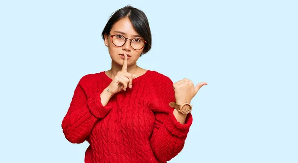 短い髪をした若い美しいヒスパニック系の女性は カジュアルなセーターや眼鏡を着て 唇の側に手を指して上の指で静かにするように求めている 沈黙と秘密の概念 — ストック写真