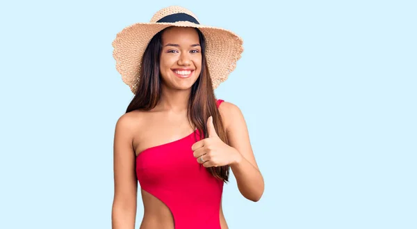 年轻美丽的拉汀女孩穿着泳衣 戴着夏帽 手拿着快乐的大拇指做手势 赞成的表情看着相机显示的成功 — 图库照片