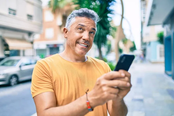 Středního Věku Šedovlasý Muž Úsměvem Šťastný Pomocí Smartphone Chůze Ulici — Stock fotografie