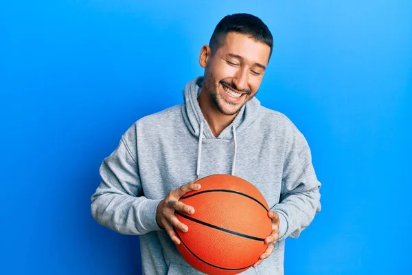 一个英俊的男人 身上有纹身 微笑着拿着篮球 笑得很大声 因为他讲了一个可笑的疯狂笑话 — 图库照片