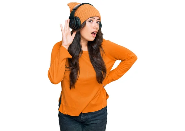 噂やゴシップに耳を傾ける耳の上に手で笑みを浮かべてヘッドフォンを使用して音楽を聞いて美しいブルネットの若い女性 聴覚障害の概念 — ストック写真