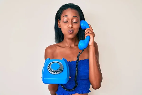 Joven Mujer Afroamericana Sosteniendo Teléfono Vintage Soplando Mejillas Con Cara —  Fotos de Stock