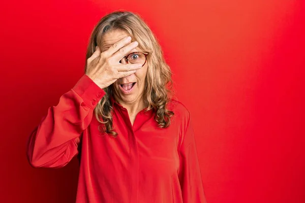Middle Age Blonde Woman Wearing Glasses Red Background Peeking Shock — Φωτογραφία Αρχείου