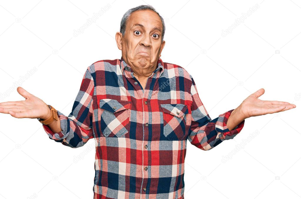 Senior hispanic man wearing casual clothes clueless and confused expression with arms and hands raised. doubt concept. 