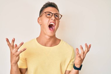 Gündelik kıyafetler giyen, gözlüklü, deli deli deli bağıran, agresif bir ifade ve kollarla bağıran genç İspanyol çocuk. hüsran kavramı. 