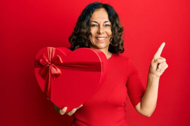 Orta yaşlı İspanyol kadın sevgililer günü hediyesini tutarken gülümsüyor mutlu bir şekilde elini ve parmağını yana doğru uzatıyordu. 