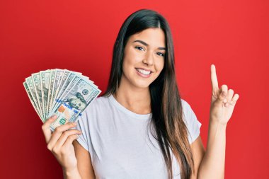 Elinde dolarlarla gülümseyen genç esmer kadın bir fikir veya soruyla mutlu bir yüzle işaret ediyor. 