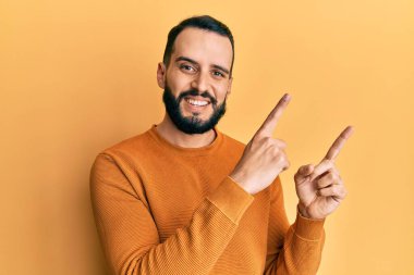 Sakallı genç adam, sıradan bir kazak giyiyor gülümsüyor ve kameraya bakıyor.. 