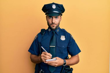 Handsome hispanic man wearing police uniform writing traffic fine skeptic and nervous, frowning upset because of problem. negative person.  clipart