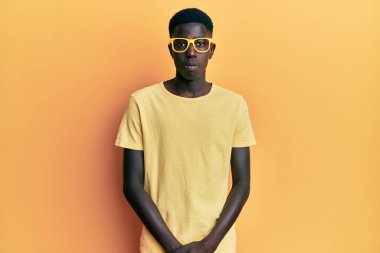 Genç, Afro-Amerikalı bir adam günlük kıyafetler ve gözlük takıyor. Depresyonda ve endişe içinde. Kızgın ve korkmuş. hüzünlü ifade. 