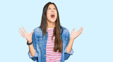 Genç esmer kadın gündelik kıyafetler giyip deli gibi bağırıyor, agresif bir ifadeyle bağırıyor ve kollarını kaldırıyor. hüsran kavramı. 