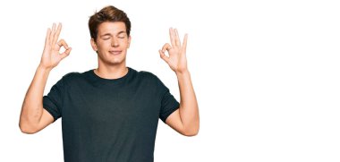 Sıradan kıyafetler giyen yakışıklı beyaz adam rahatla ve parmaklarıyla meditasyon hareketi yaparken gözleri kapalı gülümse. yoga konsepti. 