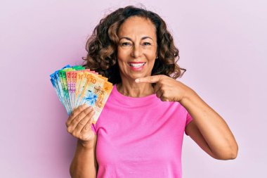 Orta yaşlı İspanyol kadın elinde İsviçre frangı banknotları tutarken mutlu mesut parmakla işaret ediyor. 