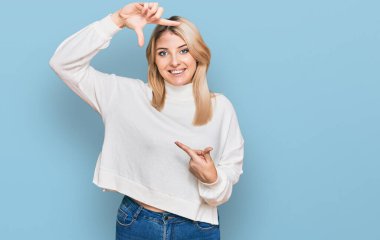 Sıradan bir kazak giyen, gülümseyen, elleri ve parmakları mutlu yüzlü genç beyaz bir kadın. yaratıcılık ve fotoğrafçılık kavramı. 