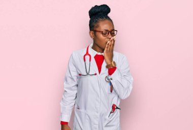 Genç Afro-Amerikan kadın doktor üniforması giyiyor ve steteskop sıkılmış esnemekten yorulmuş ağızlarını eliyle kapatıyor. Huzursuz ve uykulu.. 