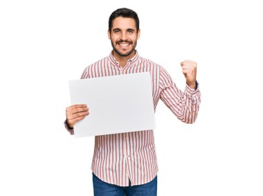 İspanyol asıllı genç adam boş bir pankart tutuyor gururla bağırıyor, zaferi kutluyor ve başarıyı kollarını kaldırarak kutluyor. 