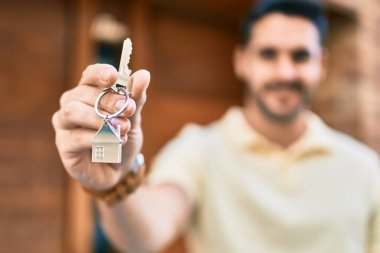 Yeni evin anahtarını tutarken mutlu gülümseyen İspanyol genç adam..