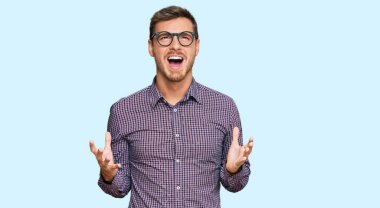 Yakışıklı beyaz adam, günlük kıyafetler ve gözlük takıyor. Deli gibi bağırıyor, bağırıyor, agresif bir ifade ve kollar havada. hüsran kavramı. 