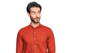 Gündelik kıyafetler giyen genç İspanyol adam gülümseyip yan tarafa bakıyor ve düşünüyor.. 