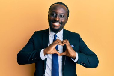 Yakışıklı, genç, siyah takım elbiseli ve kravatlı, aşkta gülümseyen, elleriyle kalp sembolü yapan. romantik kavram. 