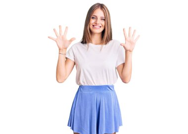 Genç, sarışın, yaz tarzı giyinen güzel bir kadın on numarayı gösterip işaret ederken kendinden emin ve mutlu bir şekilde gülümsüyor.. 