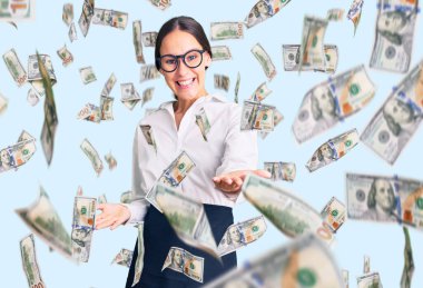 Güzel, esmer, profesyonel garson önlüğü giymiş, neşeli, kolları açık gülümseyen genç bir kadın. Hoş geldin, olumlu ve kendinden emin selamlar.