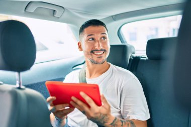 Genç İspanyol adam mutlu bir şekilde gülümsüyor. Arabada dokunmatik ped kullanıyor..