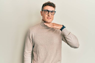 Balıkçı yaka kazak giyen İspanyol genç adam boğazını bıçak niyetine kesiyor, saldırganlığı şiddetle tehdit ediyor. 