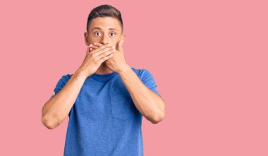 Gündelik kıyafetler giyen genç, yakışıklı İspanyol adam yanlışlıkla elleri ile ağzını kapatırken şok oldu. gizli kavram. 