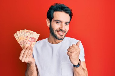 Meksika pezosu tutan genç İspanyol adam gururla bağırıyor zaferi ve başarıyı kutluyor. 