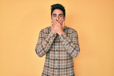 Sıradan kıyafetler giyen yakışıklı, sakallı, ağzı yanlışlıkla elleriyle kapatan bir İspanyol. gizli kavram. 