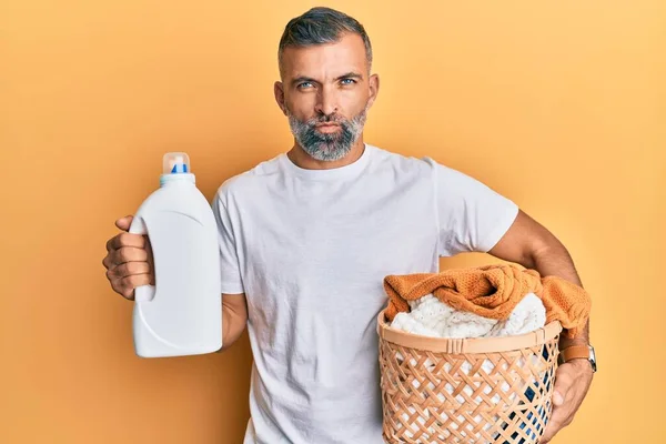 Hombre Guapo Mediana Edad Sosteniendo Cesta Ropa Botella Detergente Escéptico —  Fotos de Stock